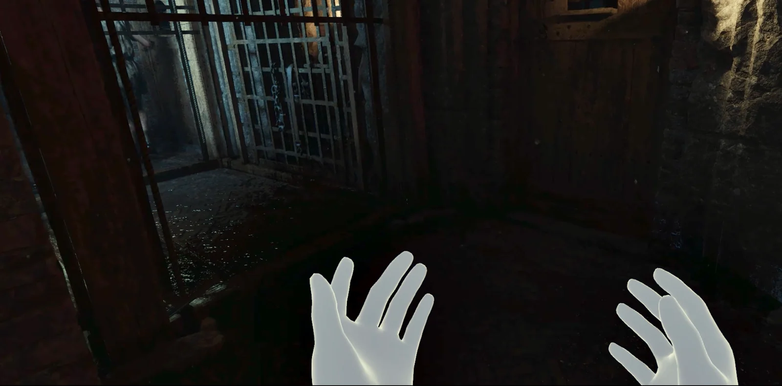 First-person view inside the hypogeum: the player's tracked hands raised in front of an iron animal cage.
